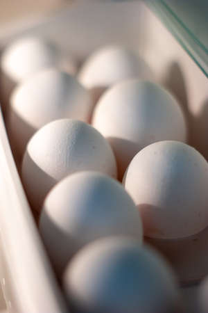 Group of white eggs stacked inside refrigerator door holder shallow depth of field.の写真素材