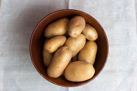 Raw potatoes in a wooden bowl top view.の写真素材