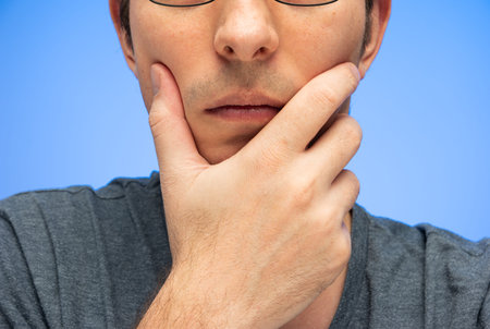 Unrecognizable cropped Caucasian male head with hand on face worried pensive gesture isolated on...