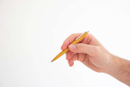Yellow vintage plastic ball pen held in hand by Caucasian male hand making gesture studio shot isolated on white.の写真素材
