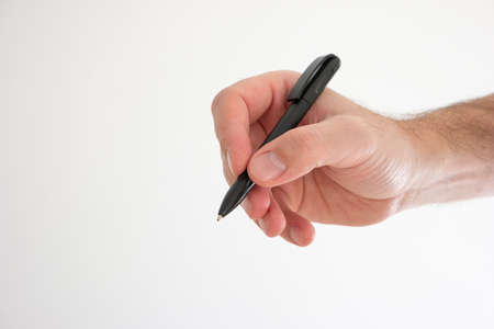 Black plastic ball pen held in hand by Caucasian male hand making gesture studio shot isolated on white.の写真素材