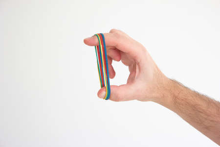 Multiple colored rubber bands stretched around Caucasian male hand fingers isolated on white.の写真素材
