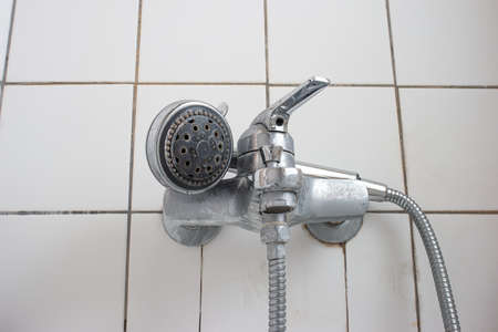 Old dirty limescale chalk covered shower head and bathtub faucet close up low angle view.の写真素材