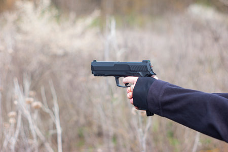 Young female arms and hands aiming a hand gun in self-defence training target practice...