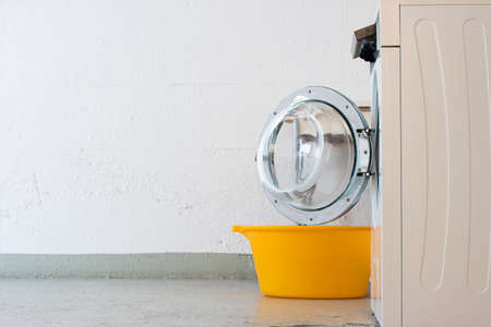Landry room washing machine open door and yellow plastic basket. Side view no people.の写真素材