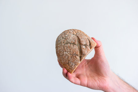 Caucasian male hand holding a moldy spoiled piece of bread.
