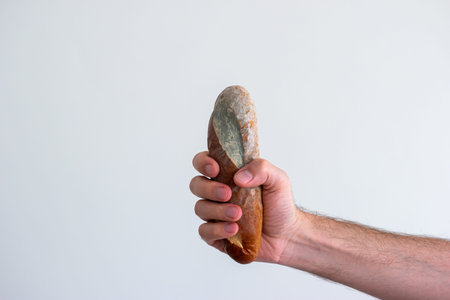 Caucasian male hand holding a moldy spoiled piece of bread.