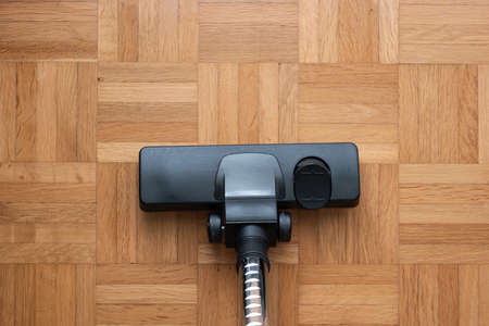 Vacuum cleaner attachment on wooden floor tiles inside room, no people, top view.の写真素材
