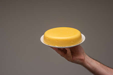 Cooked cornflower polenta on a white plate, held in hand by Caucasian male, isolated on white.の写真素材