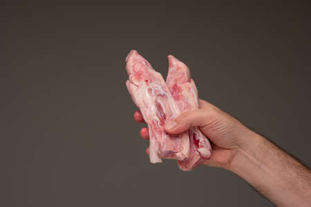 Fresh raw halved pig feet held by man's hand.の写真素材