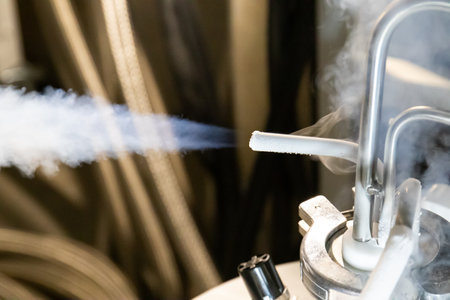 Liquid nitrogen gas emanating from pressurized tank thermal rubber hose connected to metal pipes and red hand valves.の写真素材