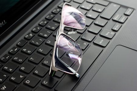 Clear reading glasses, black rim, on a laptop keypad, no people.