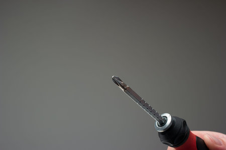 Turn screwdriver in man's hand. Close up studio shot, isolated on gray background.