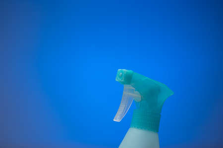 Light blue water sprayer bottle nozzle. Close up studio shot isolated on a blue background.の写真素材