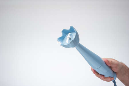 Small plastic hand food blender held in hand by male hand. Close up studio shot, isolated on white background.の写真素材