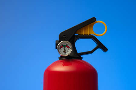 Fire extinguisher pressure gauge. Close up studio shot, isolated on blue background, no people.の写真素材