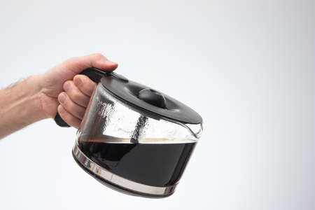 Homemade large glass coffee pot held in hand by man making a pouring gesture. Close up studio shot, isolated on white background.の写真素材