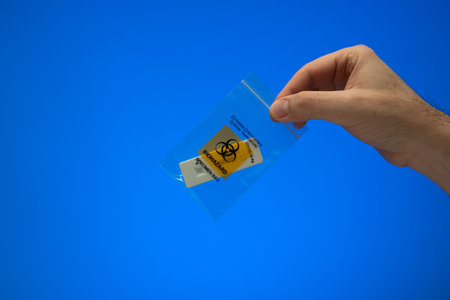 Small plastic zip bag for biowaste disposal. Biohazard specimen waste bag held by Caucasian male...