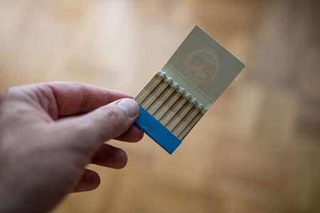 Opened old vintage box of un-burned matches held in hand by Caucasian male. Close up shot, shallow depth of field, no face.の写真素材