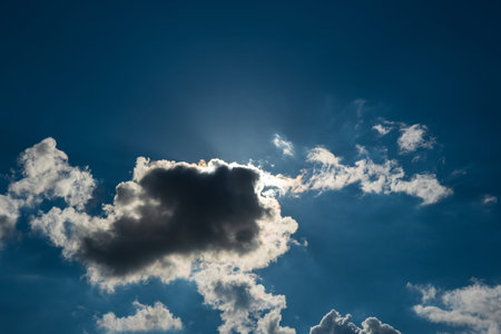 Dramatic puffy white clouds in the blue sky, sun cover behind the clouds, summed day, no people..