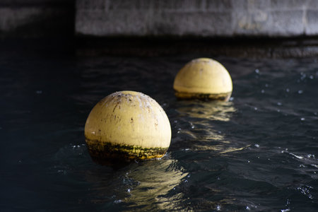 Yellow plastic buoy or buoys floating on a lake water in Switzerland, Europe. Close up telephoto shot, no peopleの写真素材