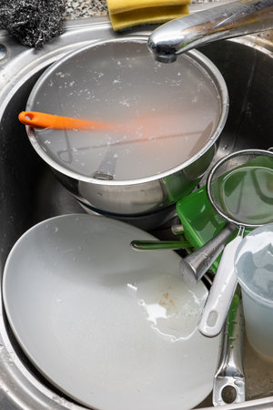 A pile of dirty dishes and utensils in a kitchen sink. Top view, no peopleの写真素材