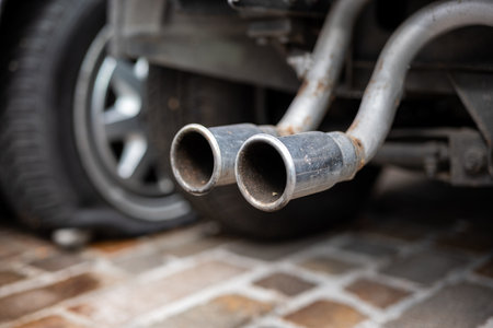 Rusty old chromed car exhaust tips hanging of a dismembered car. Low angle show, selective focus, no people.の写真素材