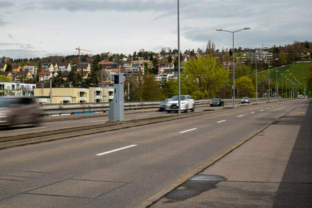 Road traffic speed trap camera in a gray box between 4 lanes of road in a major European city. Blurred traffic, slow shutter speed, no people.の写真素材