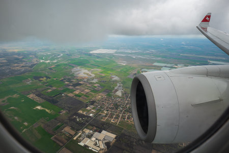 Commercial airplane flying over agricultural fields and meadows. Visible jet engine, and clouds, no...