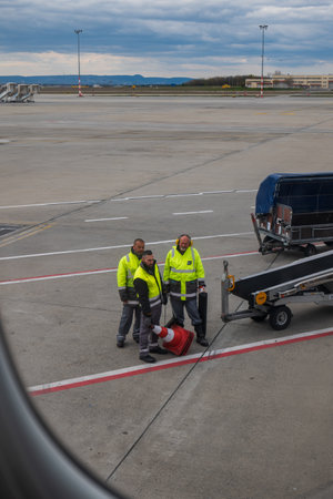 Commercial airplane luggage handlers loading baggage onto a Swiss Air plane on 04/03/2023.のeditorial素材