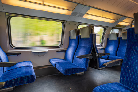 Passenger train with empty seats. Wide-angle long exposure, blurry green background out the window of an empty train in Switzerland, Europe, no peopleの写真素材