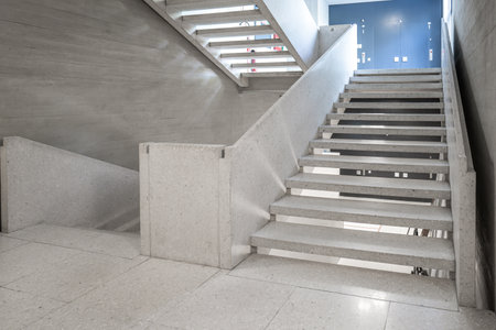 Concrete stairs in the hallway of an empty public access building. Modern architecture, bright interior space, no people.の写真素材