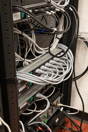 Neatly organized power cord extension cables with fully used plugs on an industrial rack. Indoors,...
