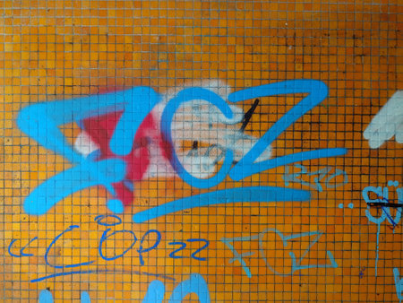 Orange ceramic tile wall vandalized with graffiti paintings. Close up shot, no people.の写真素材