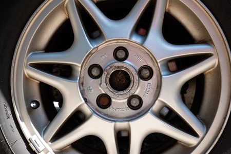 Used car alloy wheel with spokes and visible bolts. Close up shot, no people, natural light.