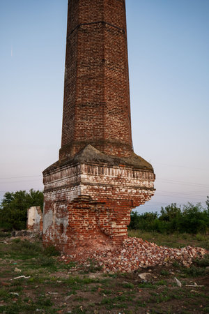 Old, run down, decaying, tall brick chimney of an abandoned urban power plant at dusk, no people.の写真素材