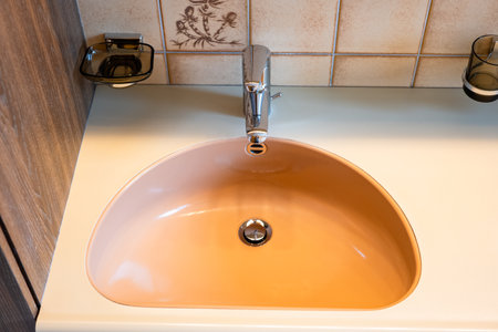 Silver, stainless steel bathroom water faucet and brown basin. Top view, no people.の写真素材