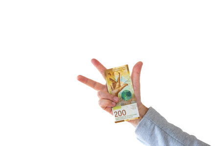 One 200 Swiss francs cash banknote or bill held by Caucasian male hand. Close up studio shot, white...