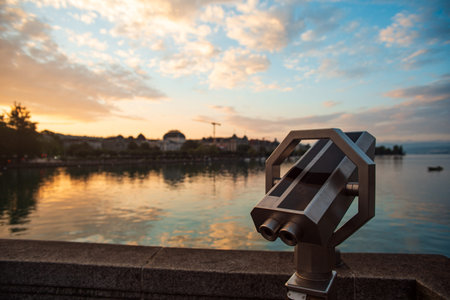 Coin operated binoculars or telescope for tourists. Summer sunrise, dramatic sky, lake water and...