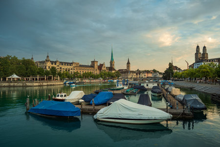 03-09-2024 Zurich, Switzerland. Touristic old part of town at sunrise. Summer dawn, famous cathedrals along the Limmat river promenade, dramatic cloudscape and water reflections.のeditorial素材