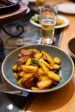 Roasted potatoes in a dish next to a glass of bear. Top, close up shot, shallow depth of field, no people.の写真素材