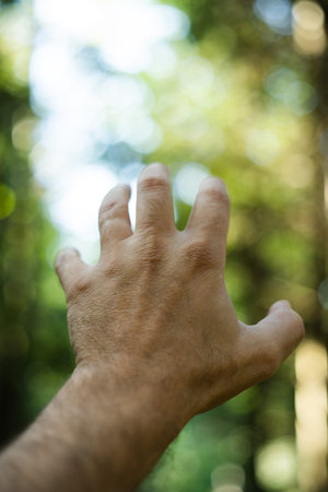 Extended Caucasian male hand gesture. Open hand and fingers reaching out and up, shallow depth of...