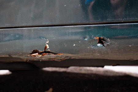 Rusty car body sill with through hole. Close up shot, no people.