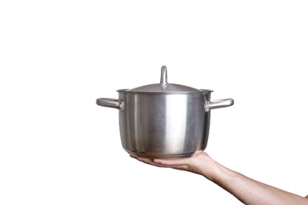 Stainless steel stock cooking pot with lid. Held by hand by Caucasian male hand. Close up studio shot, isolated on white.の写真素材