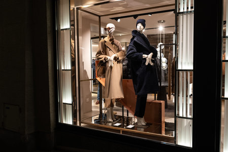 Female mannequins in store glass window display dressed casual autumn â winter elegant clothing, night scene.の写真素材