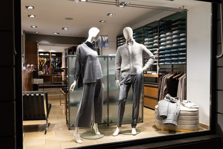 Female and male mannequins in store glass window display dressed casual autumn â winter elegant clothing, night sceneの写真素材