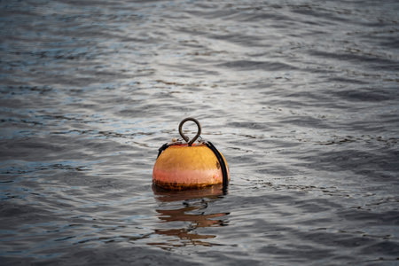 Orange, round buoy floating on a lake water. Close up shot, no people.の写真素材