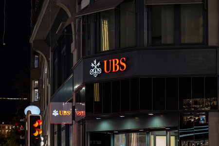 18-11-2024, Zurich, Switzerland. UBS bank large red logo on building front at night. Lit up, dark scene, close up shot, no peopleのeditorial素材