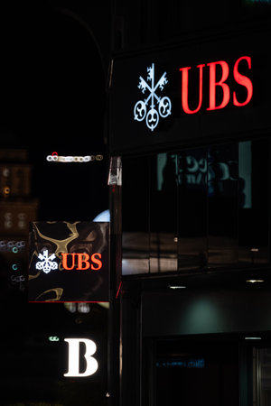 18-11-2024, Zurich, Switzerland. UBS bank large red logo on building front at night. Lit up, dark scene, close up shot, no peopleのeditorial素材