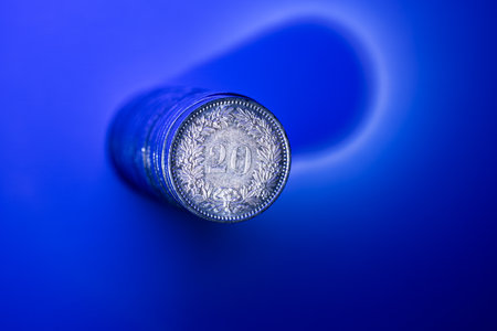 A stack of 20 Rappen Swiss Franc currency coins. Top view, isolated on blue, close up shot, no people.の写真素材